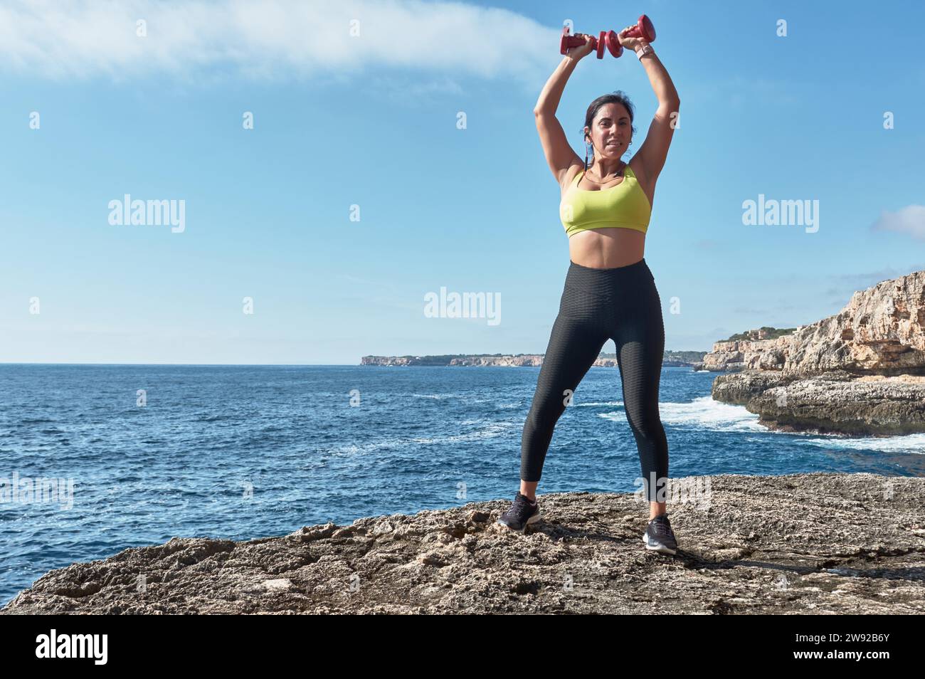 Latin woman, middle-aged, wearing sportswear, training, doing physical exercises, plank, sit-ups, climber's step, burning calories, keeping fit Stock Photo