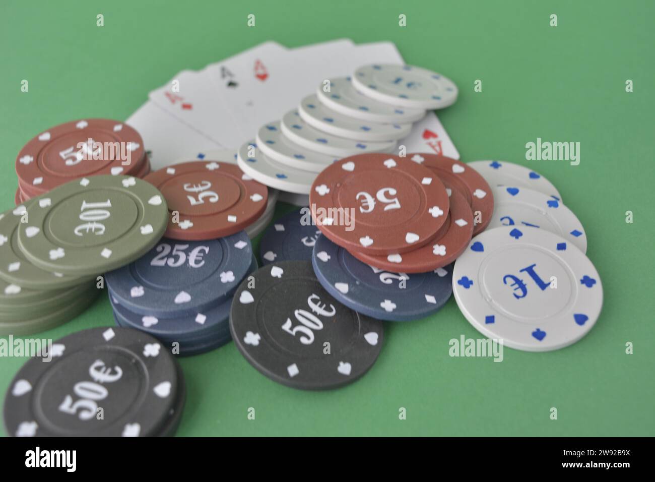 Stacks of poker chips and a fan of playing cards on a green felt gaming table, poker cards and chips Stock Photo