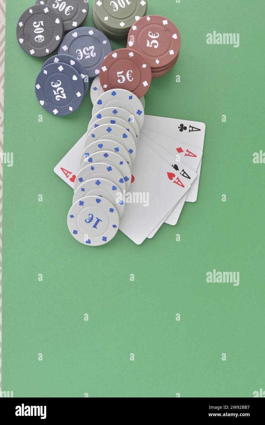 Poker chips neatly arranged with playing cards featuring aces on a green felt surface, poker cards and chips Stock Photo