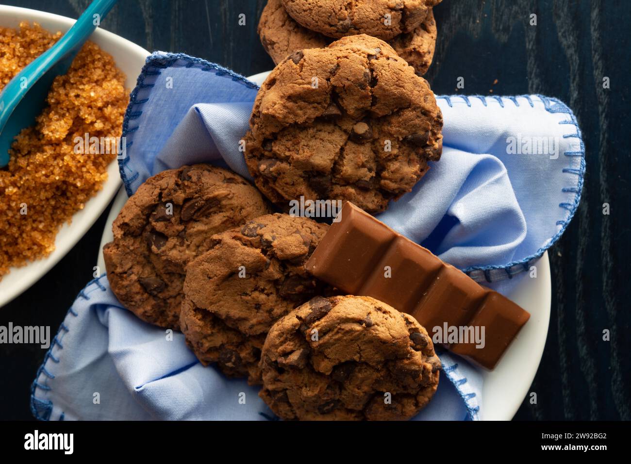 Chocolate chip cookies on a white plate beside brown sugar and a piece of milk chocolate, top view chocolate cookies. Resolution and high quality Stock Photo