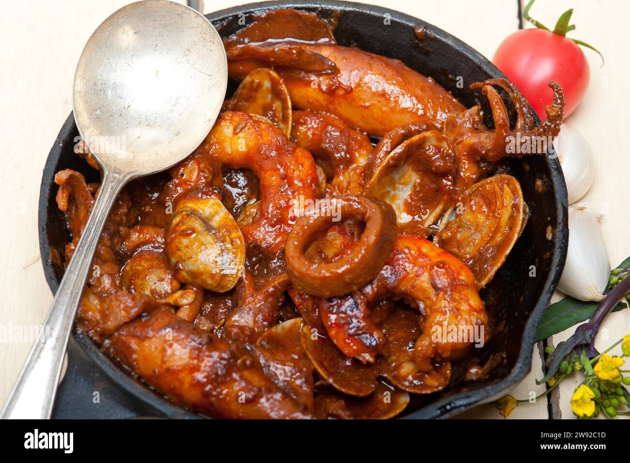 Fresh seafood stew prepared on an iron skillet ove white rustic wood table, Food photography Stock Photo