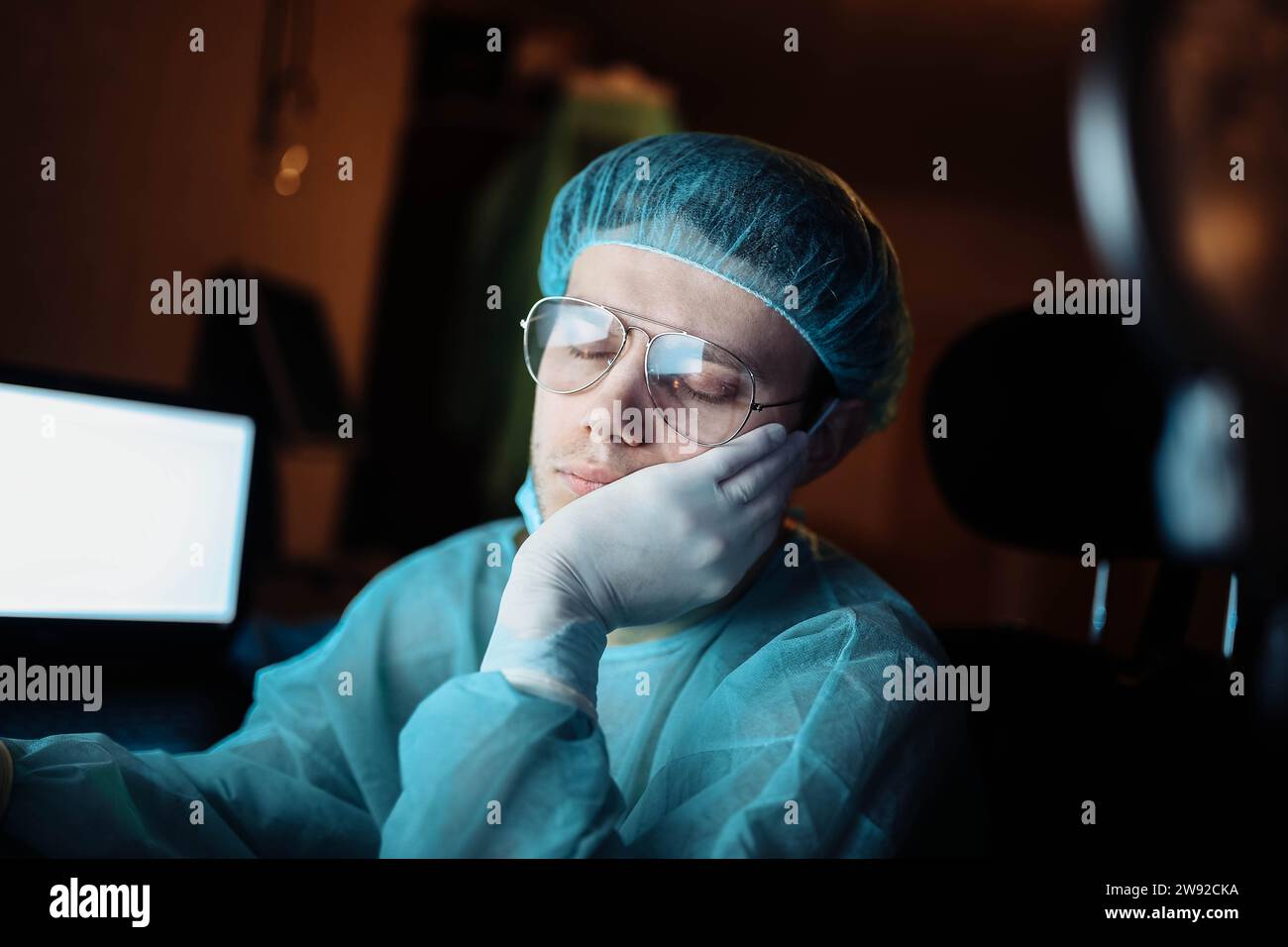 A tired young surgeon falls asleep in the resident's room after hours of complex surgery Stock Photo