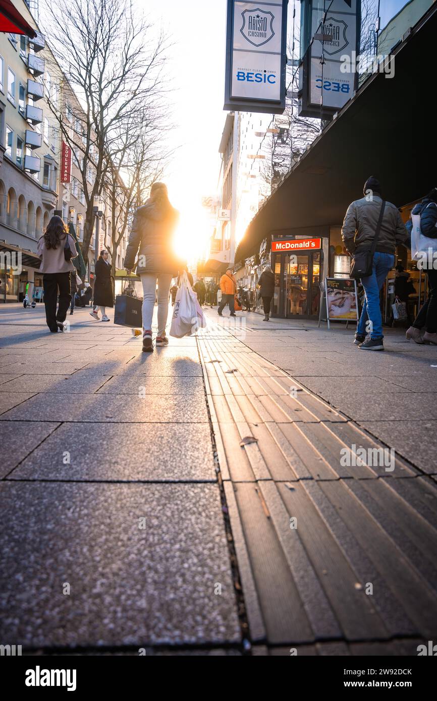 City life with people shopping on a busy street at sunset, Stuttgart ...