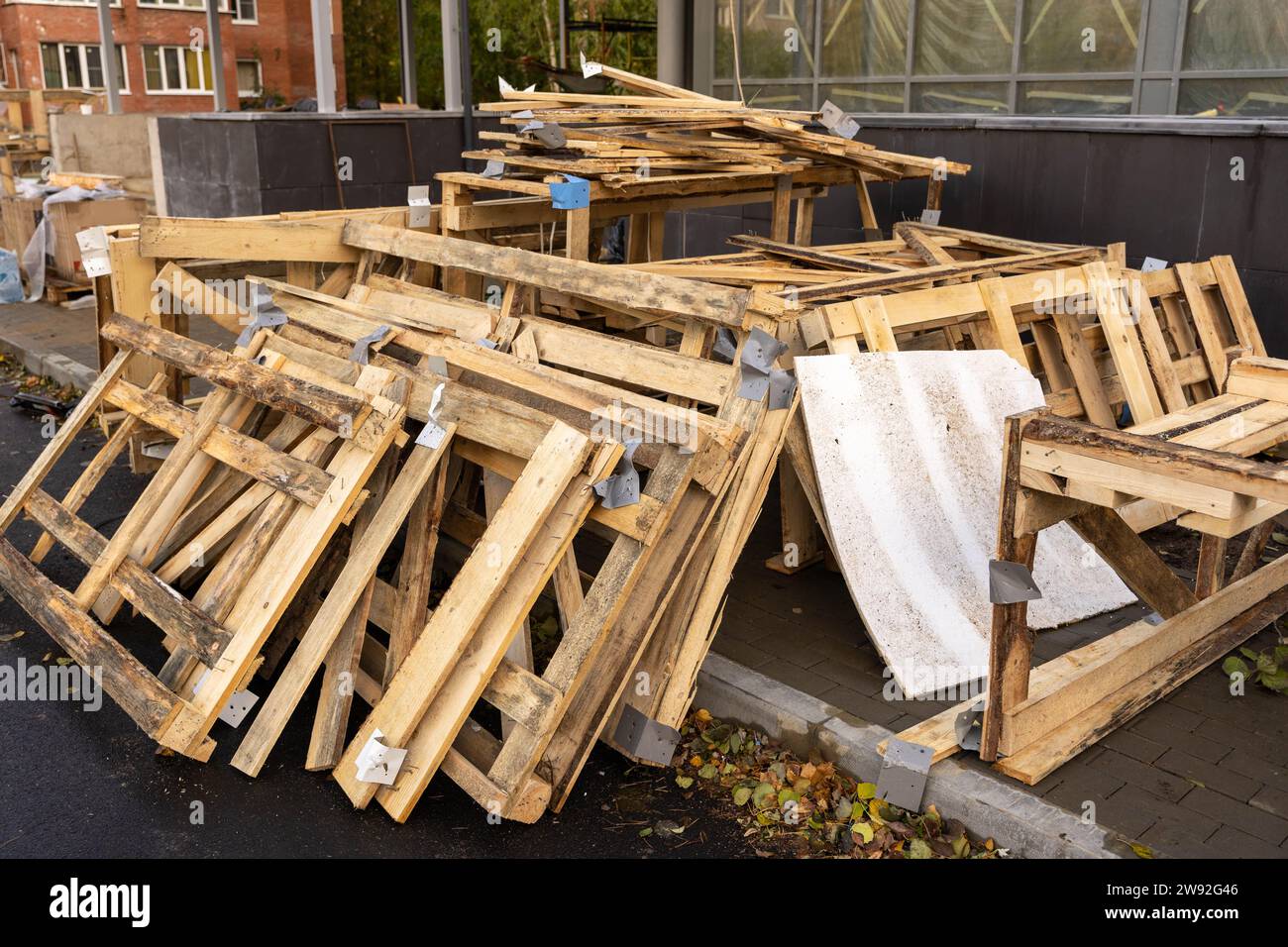 A disassembled wooden crate with stacked planks on a construction site