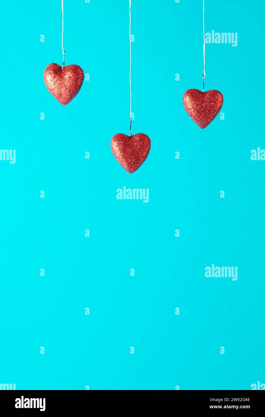Three red hearts in fish hooks on a blue background. Love concept. Copy