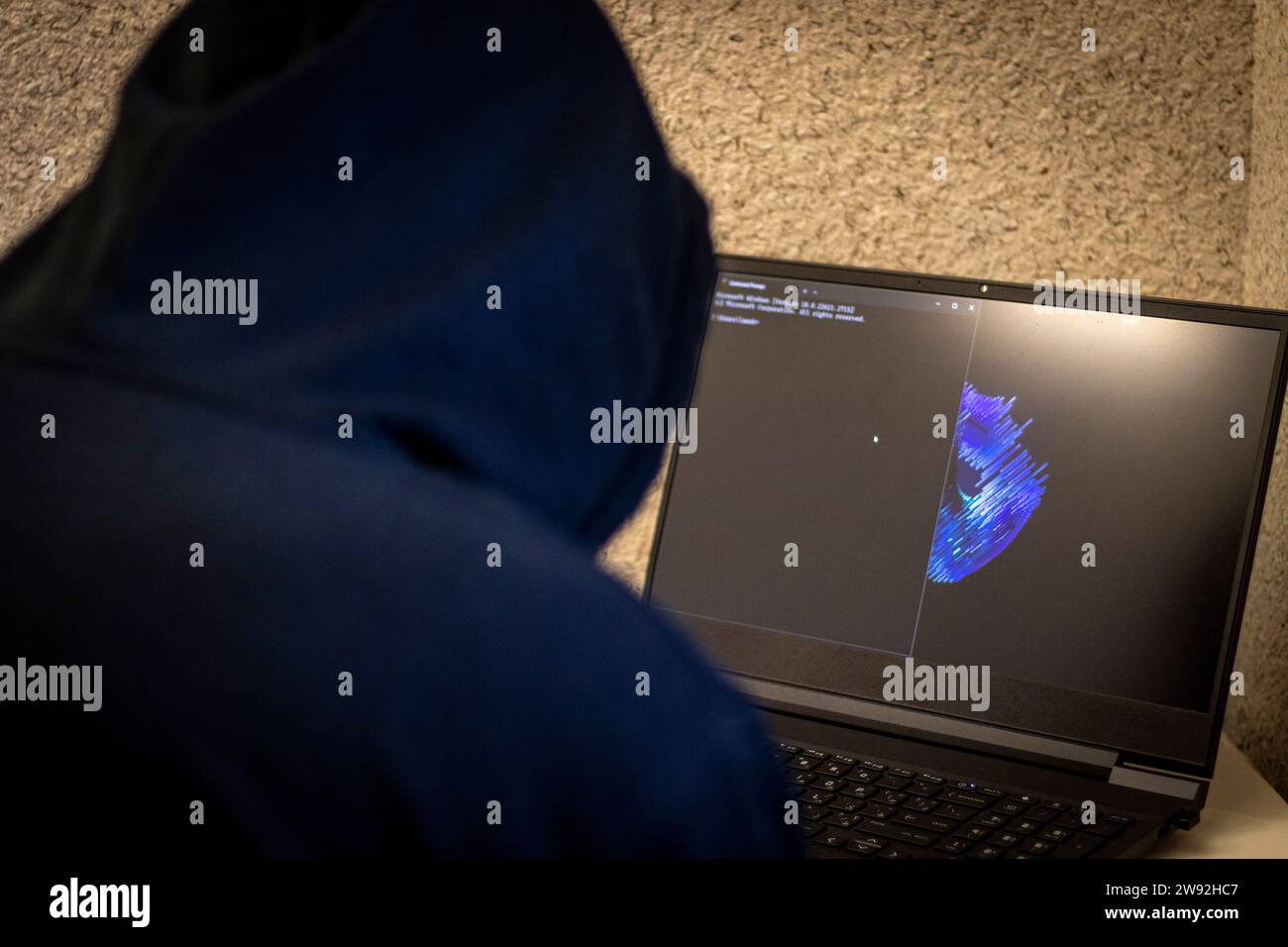 Man looked like hacker in a hood sitting in the front of laptop ...