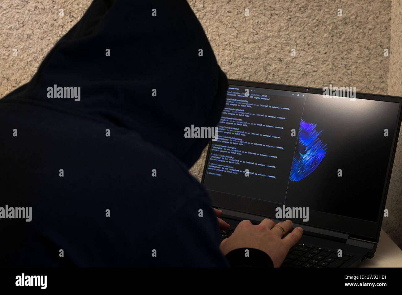 Man looked like hacker in a hood sitting in the front of laptop ...