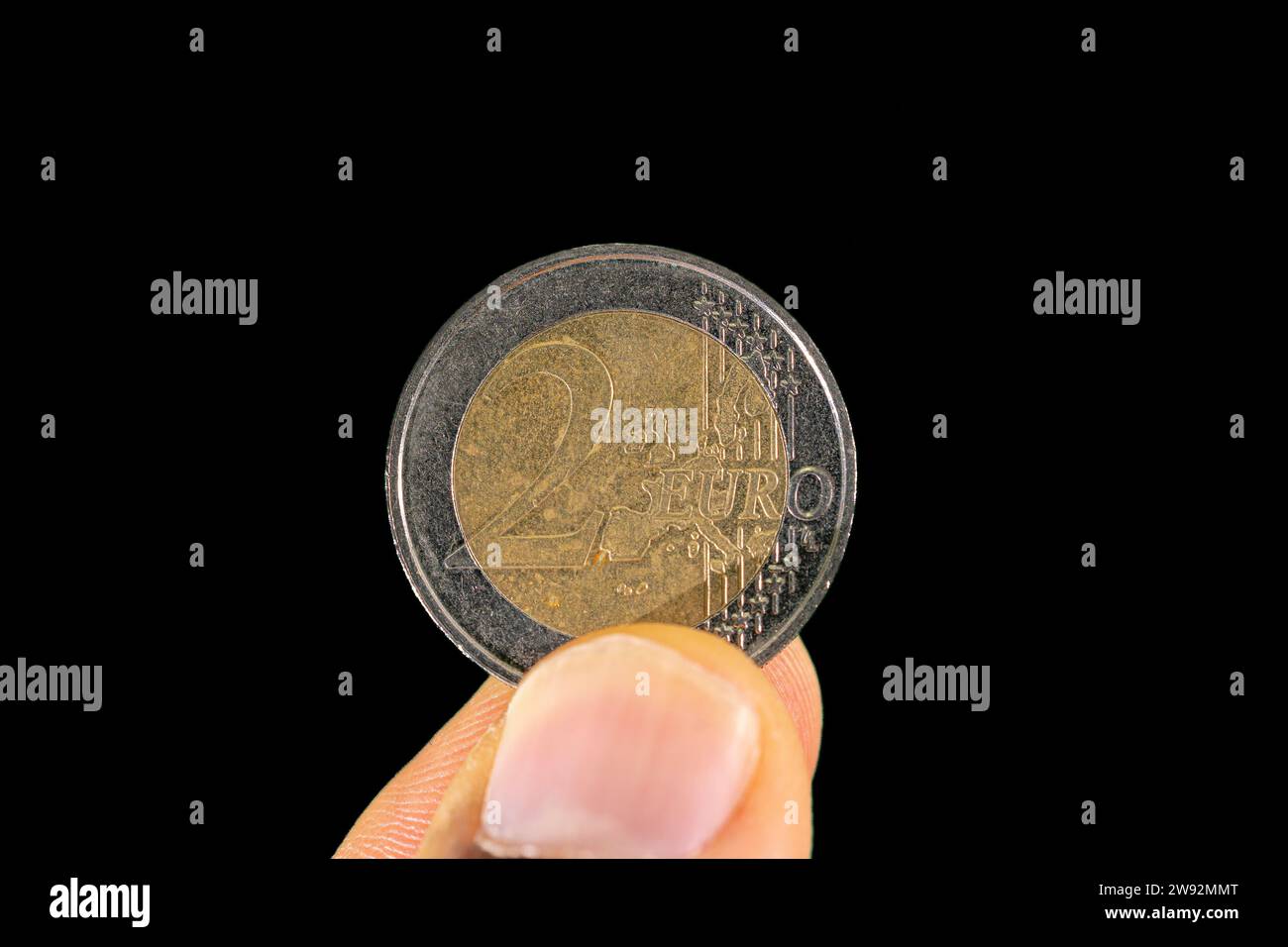 2 euro coin face held between thumb and index finger Stock Photo