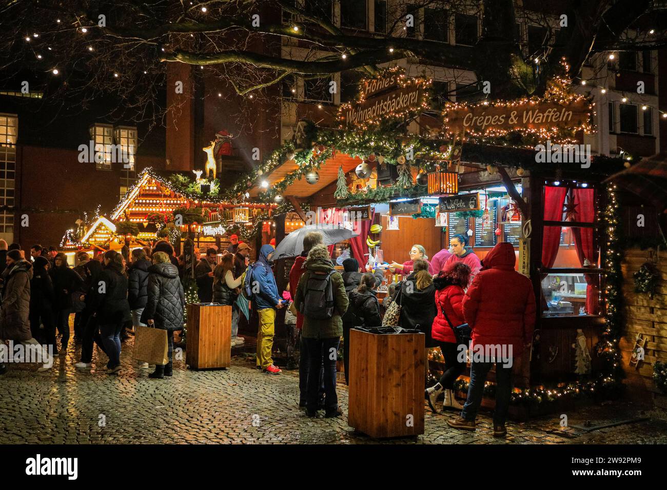 Münster, NRW, Germany. 23rd Dec, 2023. Shoppers stop for mulled wine on one of the city's six Christmas markets, open for the last day today. Christmas shoppers and tourists stroll along the pretty, medieval Prinzipalmarkt street in Münster's old town on a rainy last shopping day before Christmas Eve. Credit: Imageplotter/Alamy Live News Stock Photo