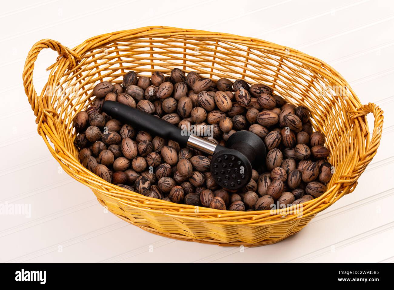 Pecan nuts in a wicker basket with rubber hammer for cracking, isolated on white Stock Photo Alamy