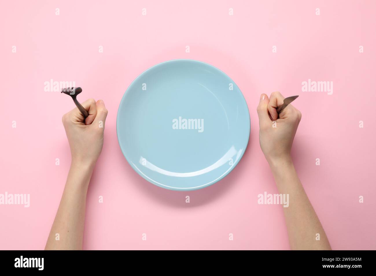 Woman with fork, knife and empty plate at pink table, top view Stock ...