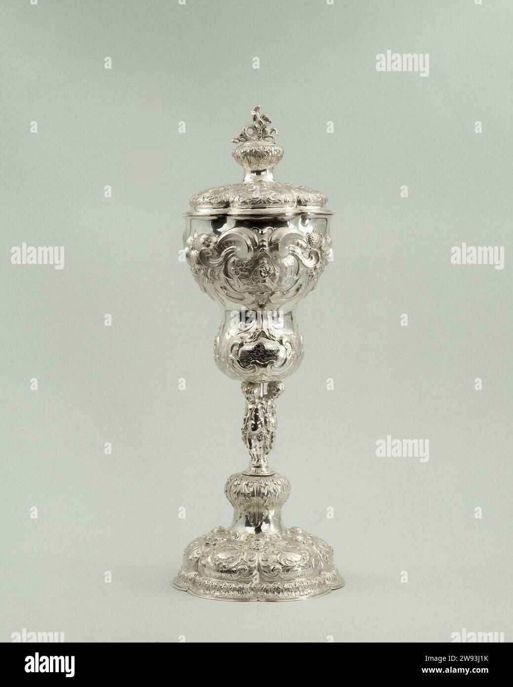 Cup of Zwartsluis, Johan Kuynder, 1676 goblet Bokaal, silver with lid, decorated with floating, on the cuppa the allegories of war, peace and justice with appropriate poems. The cuppa rests on three children's figures with grape bunches. On the foot six weapons with the captions: Gerryt Kloecken; Pieter Jansen, Swarte Suis; Roelof Stroombergh, Jan van Steenwijck, Fransisalana. On the lid the Wapen van Oranje and the portraits of the Prinsen Willem I, Maurits, Fred. Hendrik, Willem II and Willem III. As a crowning Neptunus driving on a hippocampus. On the inside a portrait with the caption Hend Stock Photo