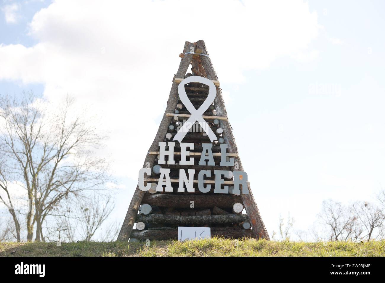 Reserve, USA. 23rd Dec, 2023. A sign to Heal Cancer is displayed on a bonfire on the River Road