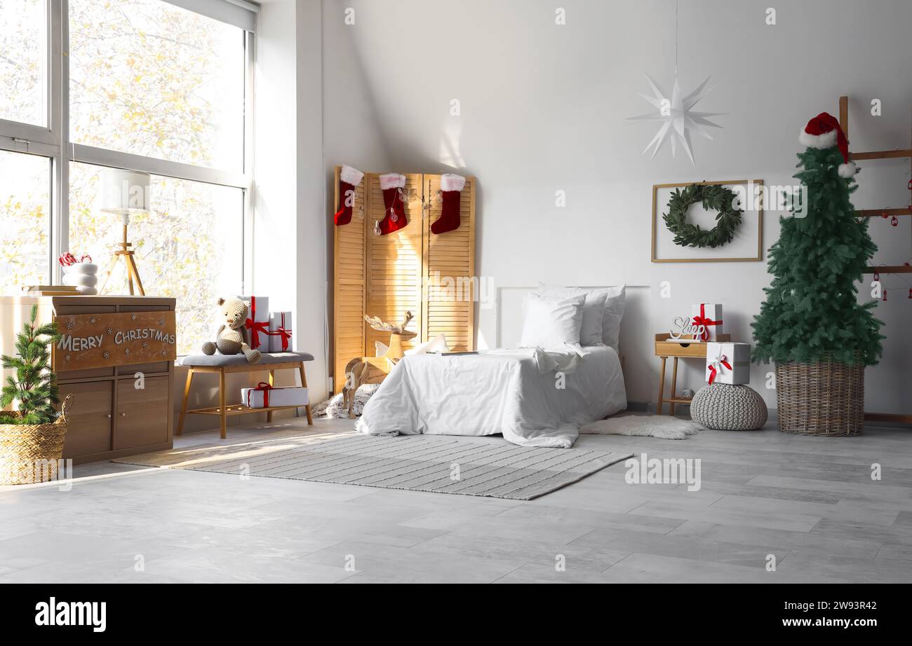 Interior of festive children's bedroom with cozy bed and Christmas decorations Stock Photo