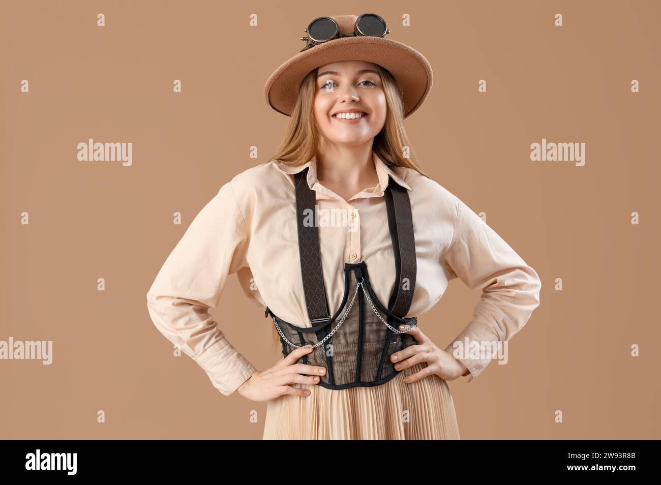 Stylish young woman in steampunk goggles on beige background Stock Photo