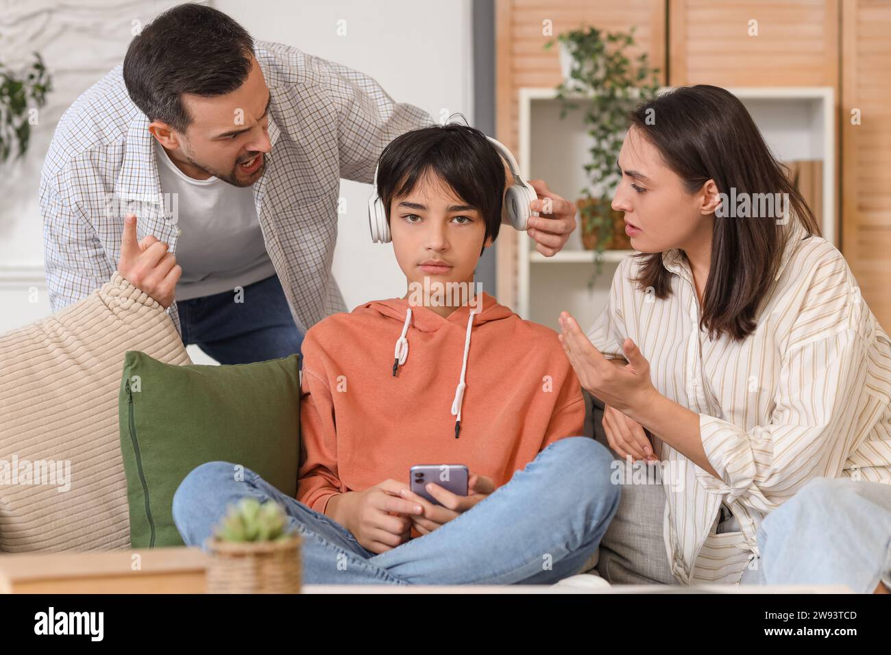 Angry parents arguing with their teenage son in headphones at home ...