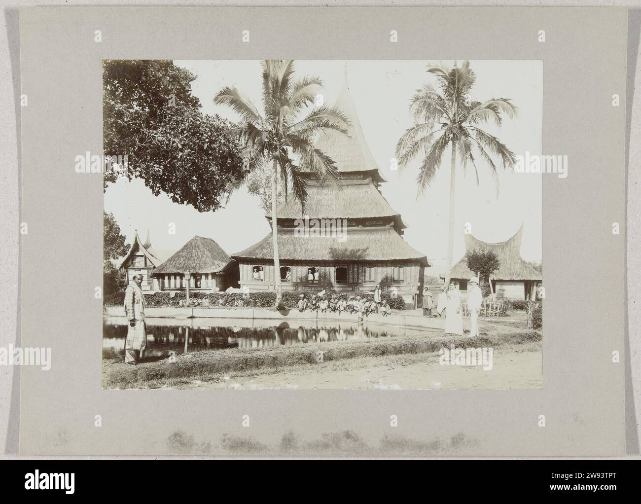 Mosque with fishing pond in Kampong Taluk at Fort de Kock, c. 1895 - c. 1915 photograph Mosque with fishing pond in Kampong Taloek at Fort de Kock, Sumatra, the Dutch East Indies. On the right a Western couple, children at the edge of the pond. Sumatra photographic support. paper. cardboard gelatin silver print  Indonesia Stock Photo