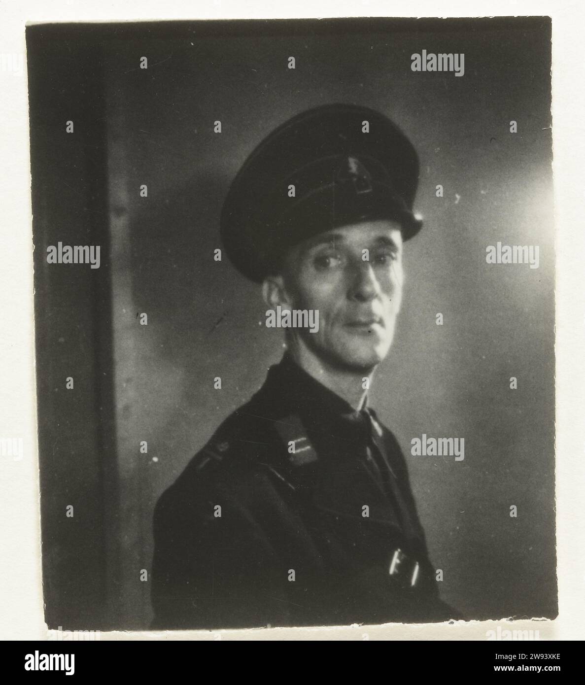 Portrait of a member of De Wa, 1940 - 1944 contact print Portrait of a member of the WA. On his collar a distinctive with two stripes: watchmaster, men. Belt diagonally over the chest. Pet with wolfsangel on his head. Lean face. Netherlands photographic support gelatin silver print anonymous historical person portrayed Netherlands Stock Photo