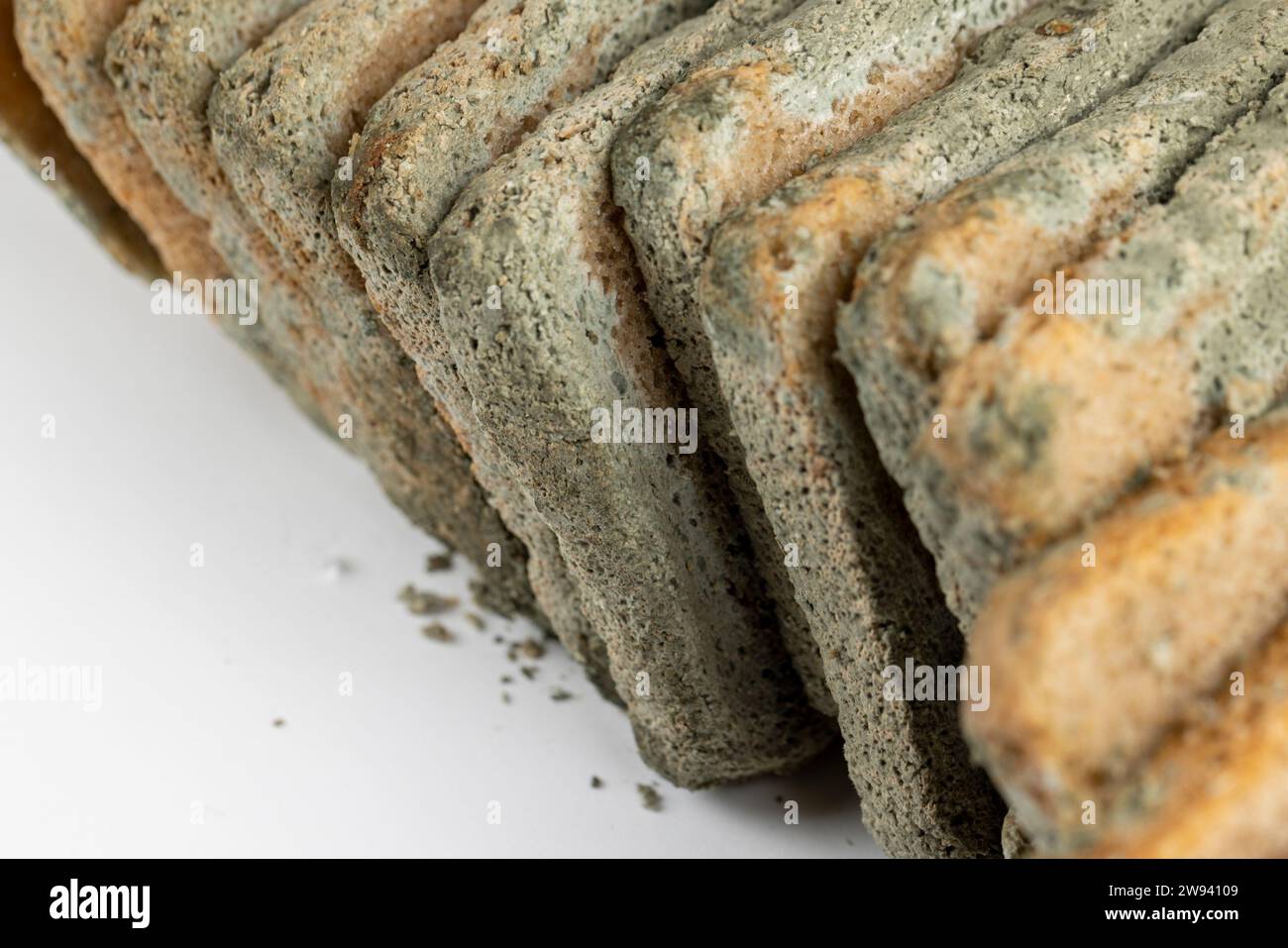 dangerous pieces of bread covered with mold on the table, a loaf of bread made of wheat and rye flour spoiled by bacteria and mold Stock Photo