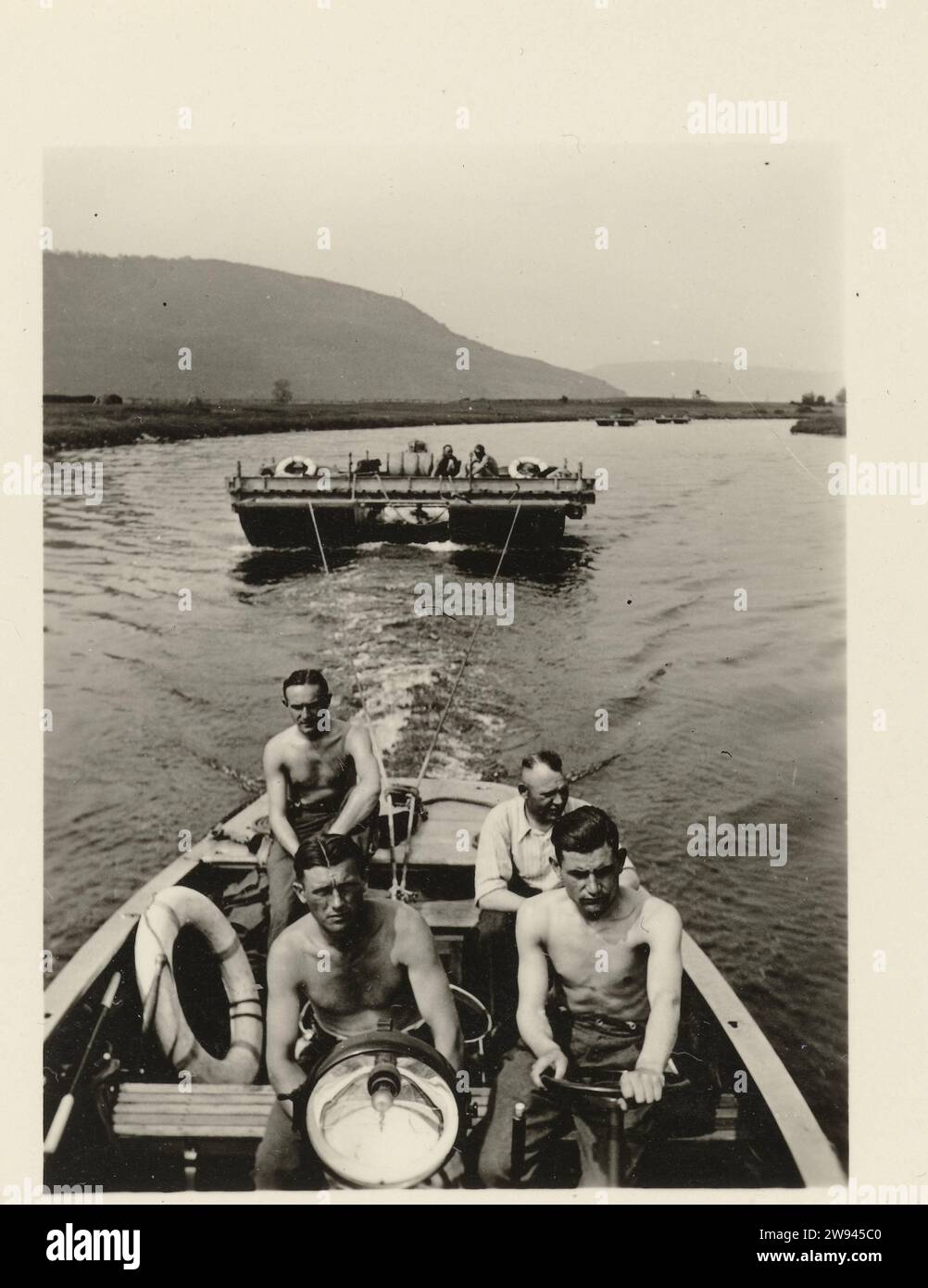 Four men in a boat, 1940 - 1945 photograph Four men in a boat. The boat pulls a different type of boat. On the back it says: laundry sauce. In HX. Photo belonging to album 'KriegSerinnerungen'. Germany photographic support gelatin silver print  Germany Stock Photo