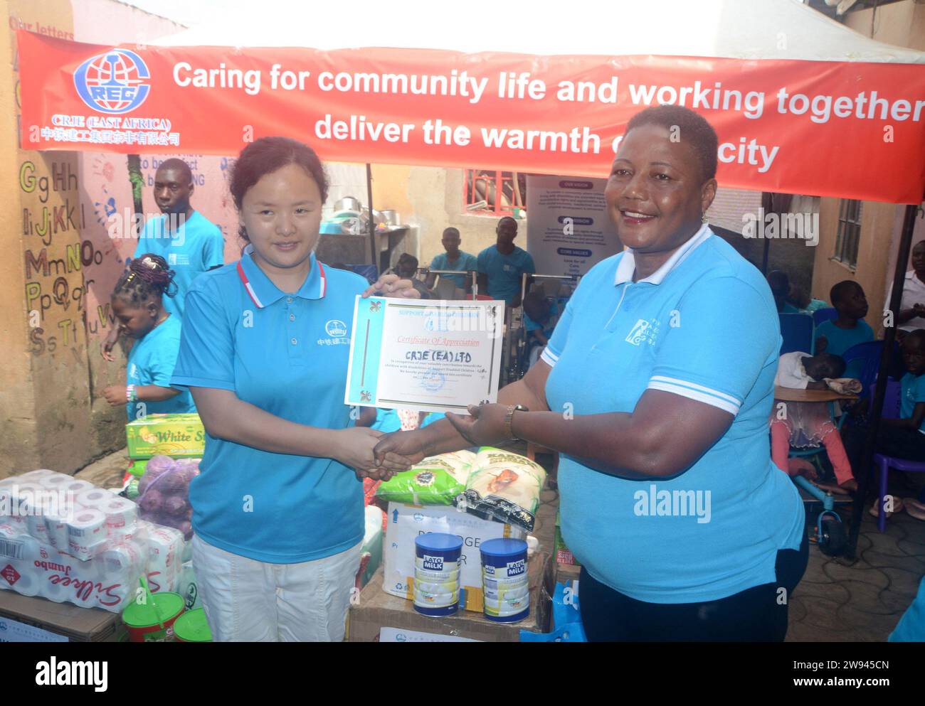 (231224) -- KAMPALA, Dec. 24, 2023 (Xinhua) -- Betty Nankabirwa (R), the founder of Support Disabled Children Ggaba (SDCG), a charity organization looking after children with special needs, hands over a certificate of appreciation to Lei Xue, an executive of Chinese enterprise CRJE (East Africa) Limited, during the donation ceremony in Kampala, Uganda, Dec. 23, 2023. Chinese enterprise CRJE in Uganda, a subsidiary of China Railway Construction Engineering Group Co. Ltd, has supported children with disabilities here with home-use items and food ahead of Christmas celebrations. The supply includ Stock Photo