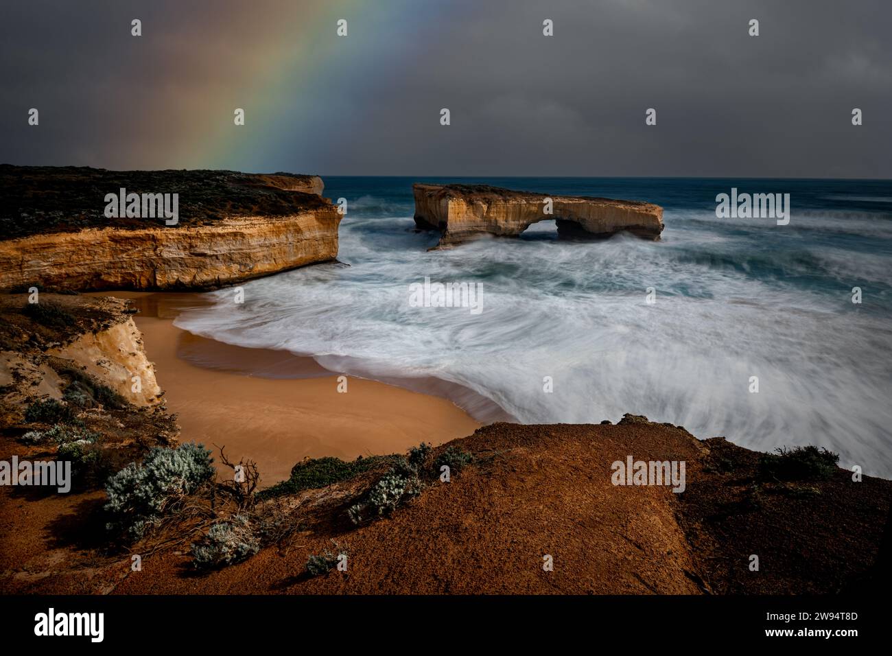 Rainbow over famous London Bridge in Port Campbell National Park. Stock Photo