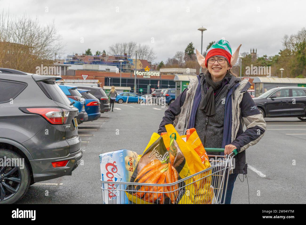 Kidderminster, UK. 24th December, 2023. UK weather: a bright smile on a dull Christmas Eve brightens the day. Last minute shopping, getting in the essentials for Christmas and this happy shopper seems relieved to be heading home to enjoy the Christmas festivities. Credit: Lee Hudson/Alamy Live News Stock Photo