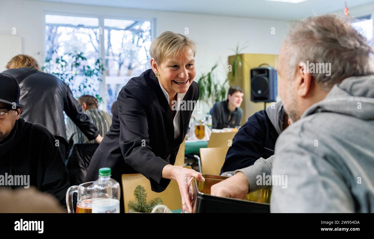 Hamburg, Germany. 24th Dec, 2023. Bishop Kirsten Fehrs, acting chair of the Council of the Evangelical Church in Germany (EKD), gives out angels as good luck charms to visitors at the Diakonie day center for homeless people. Credit: Markus Scholz/dpa/Alamy Live News Stock Photo