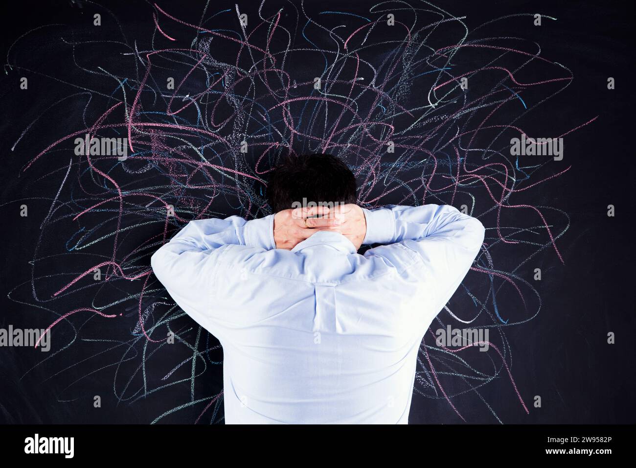 Stressed man looking to a chalkboard with lots of crazy lines Stock Photo