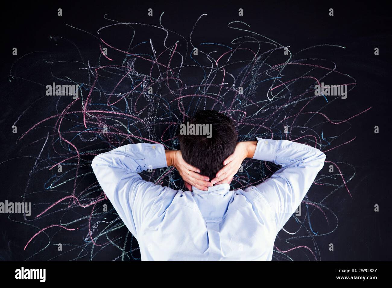Stressed man looking to a chalkboard with lots of crazy lines Stock Photo