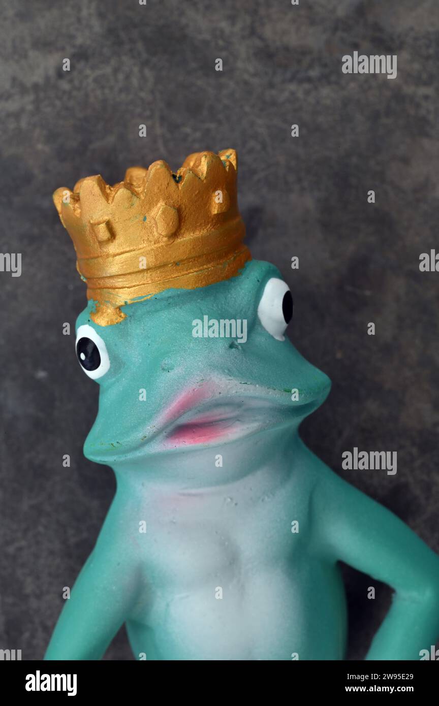 Head and shoulders of model of blue green frog with bulbous eyes and pink mouth and wearing gold crown Stock Photo