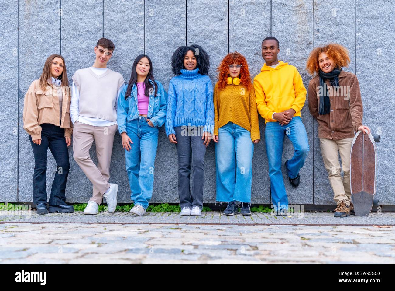 Portrait of a multi-ethnic group of friends standing leaning on an urban wall Stock Photo