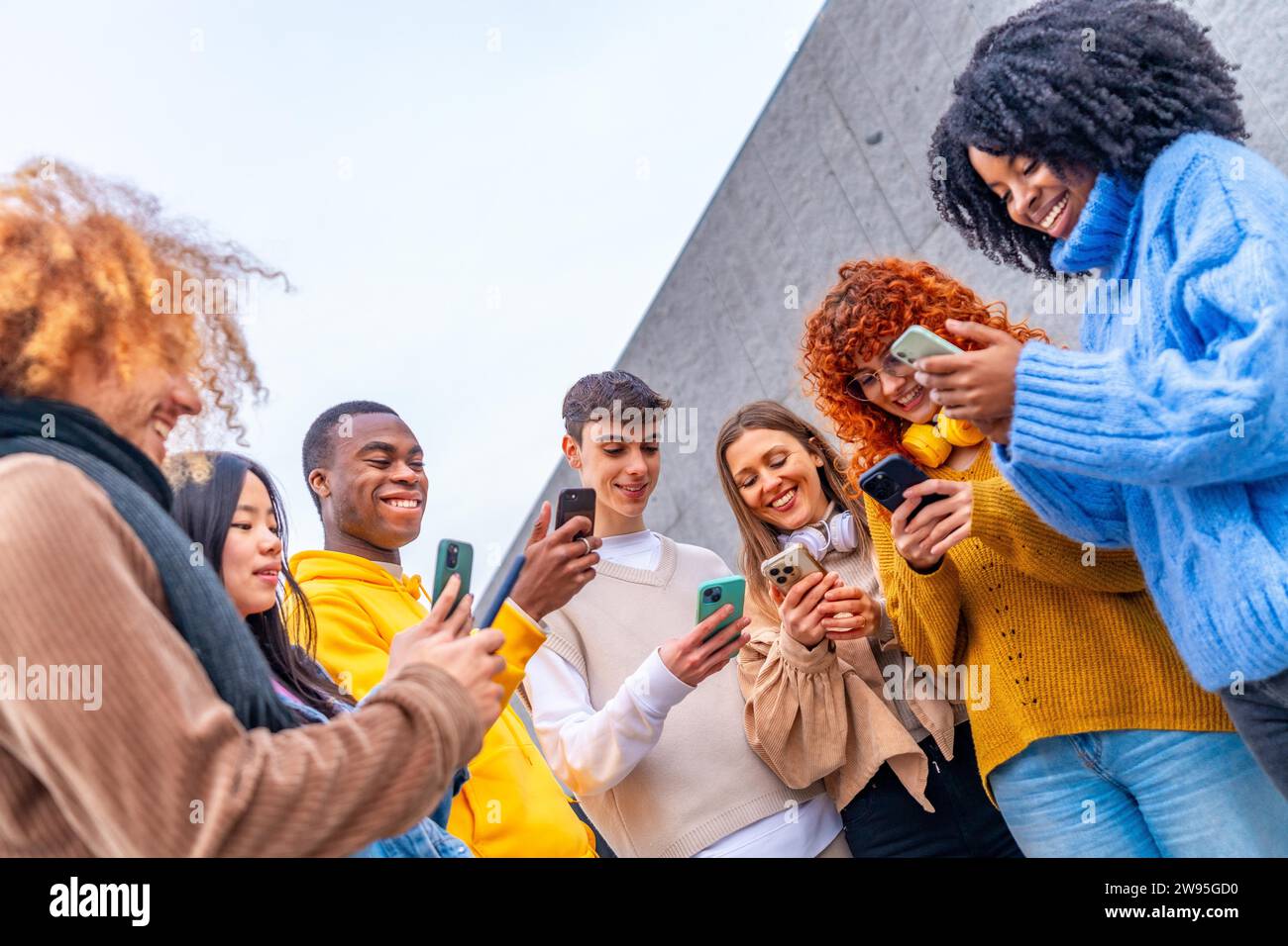 Low angle view of a group of friends using phone in the city Stock Photo