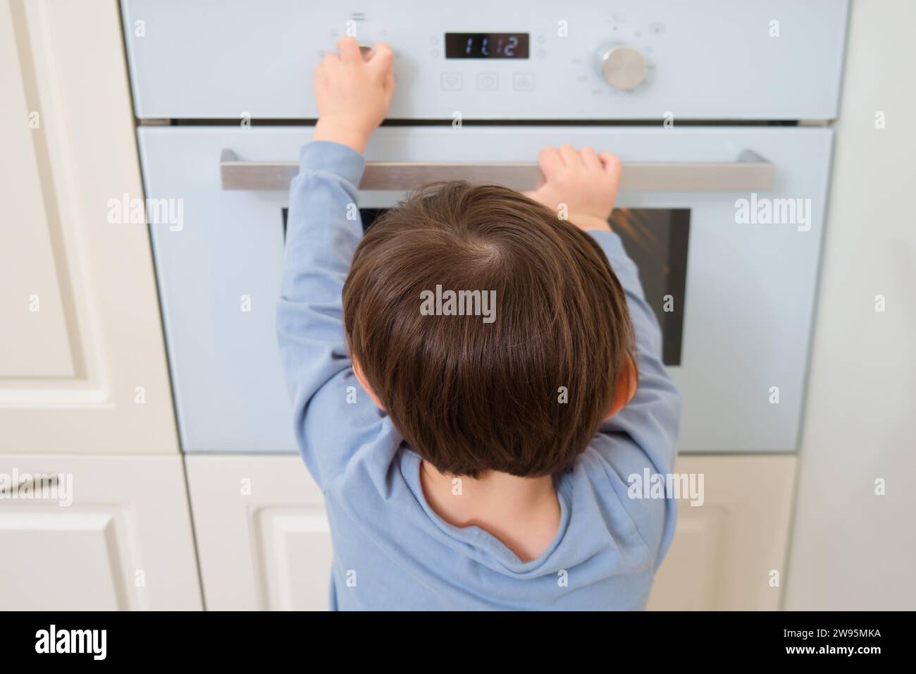 Child using a microwave oven in the kitchen at home. Kid aged two (two