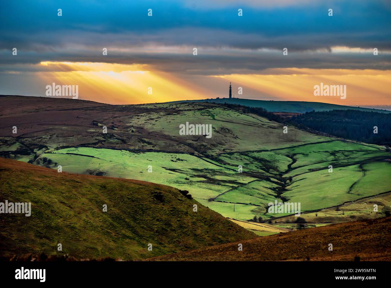 Setting sun over the Peak district hills looking across Wildboarclough towards the Congleton television transmitter. Stock Photo