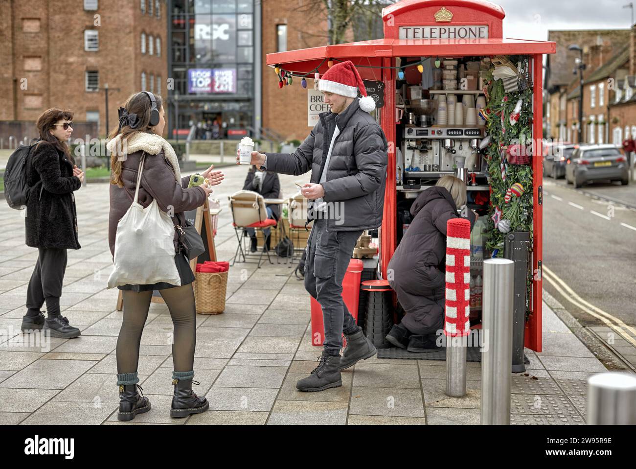 Pavement coffee outlet from a converted telephone kiosk with customers being served by barista