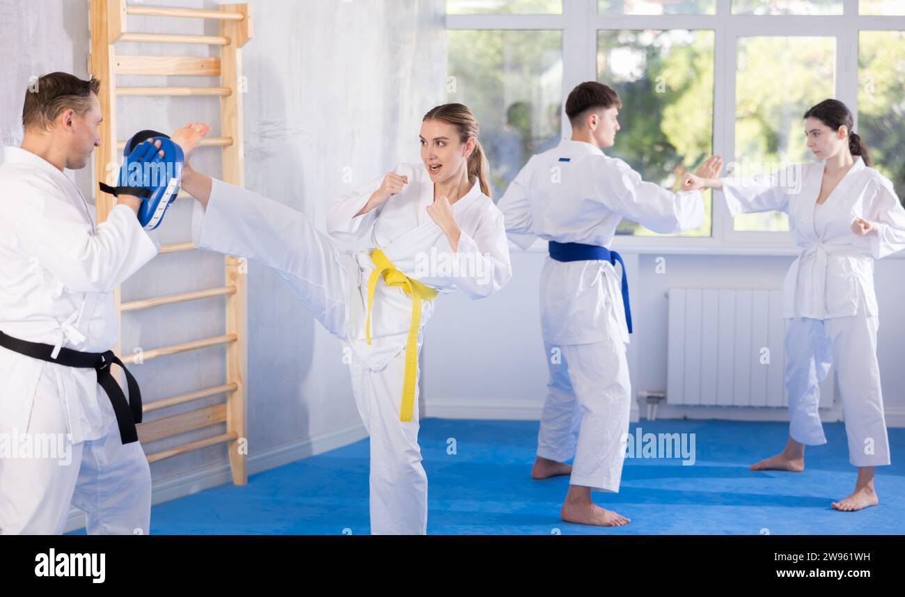 Young girl training kicks on punch mitts held by instructor Stock Photo