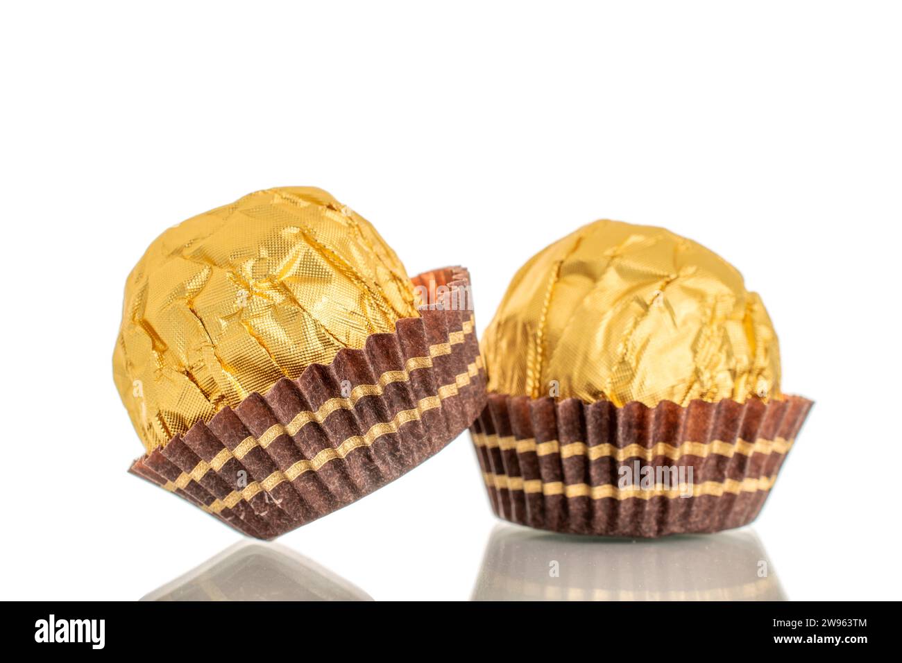 Two chocolate candies with a nut in a paper wrapper, macro, isolated on ...