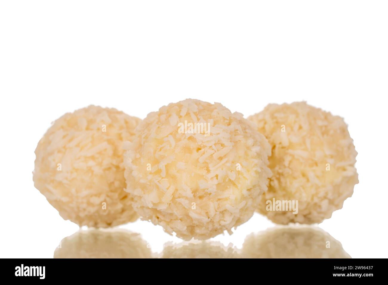 Three candies with nut and coconut flakes, macro, isolated on white background. Stock Photo