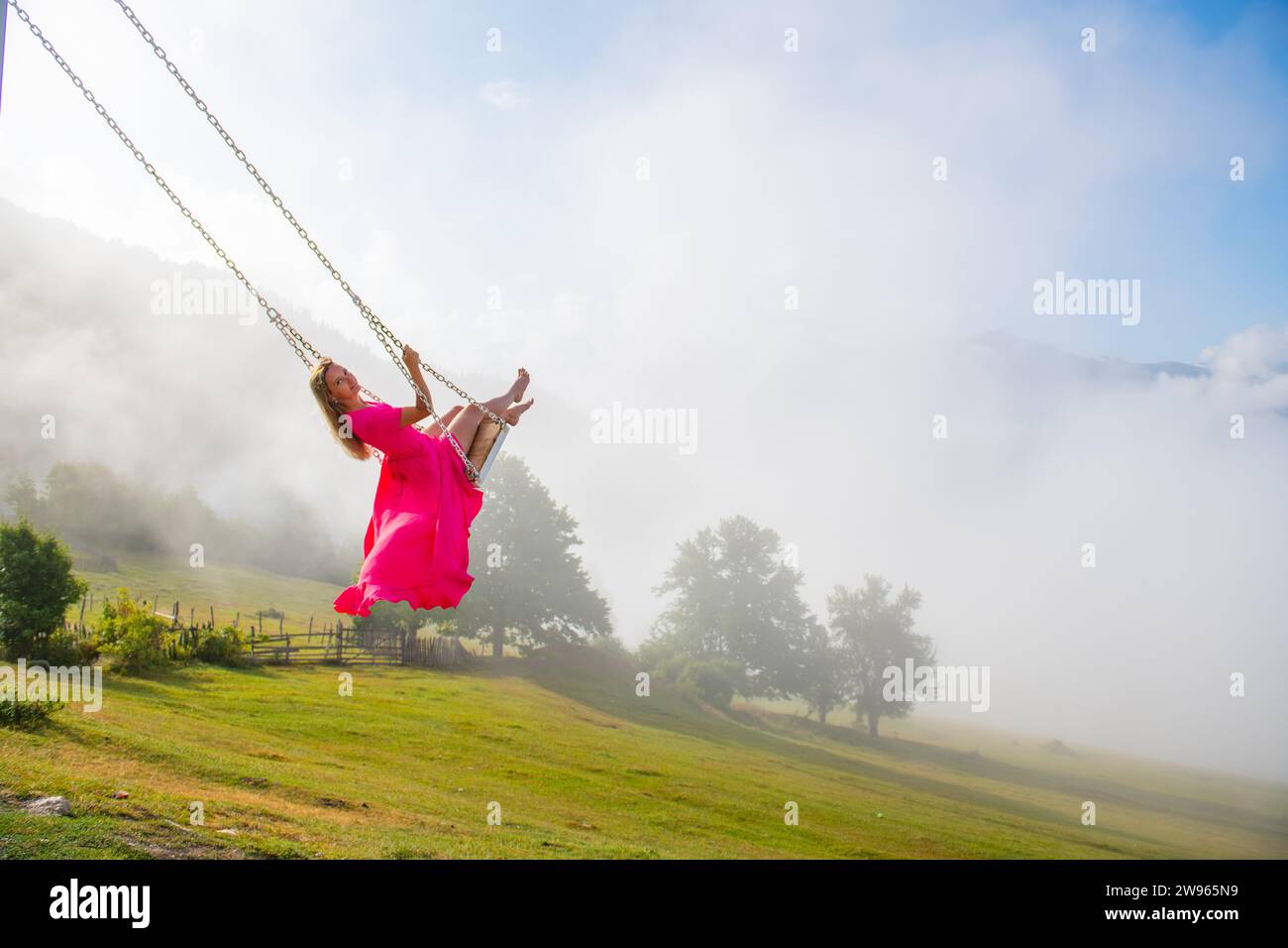 Rotate in the ethereal elegance of a swing girl in a pink dress Stock Photo
