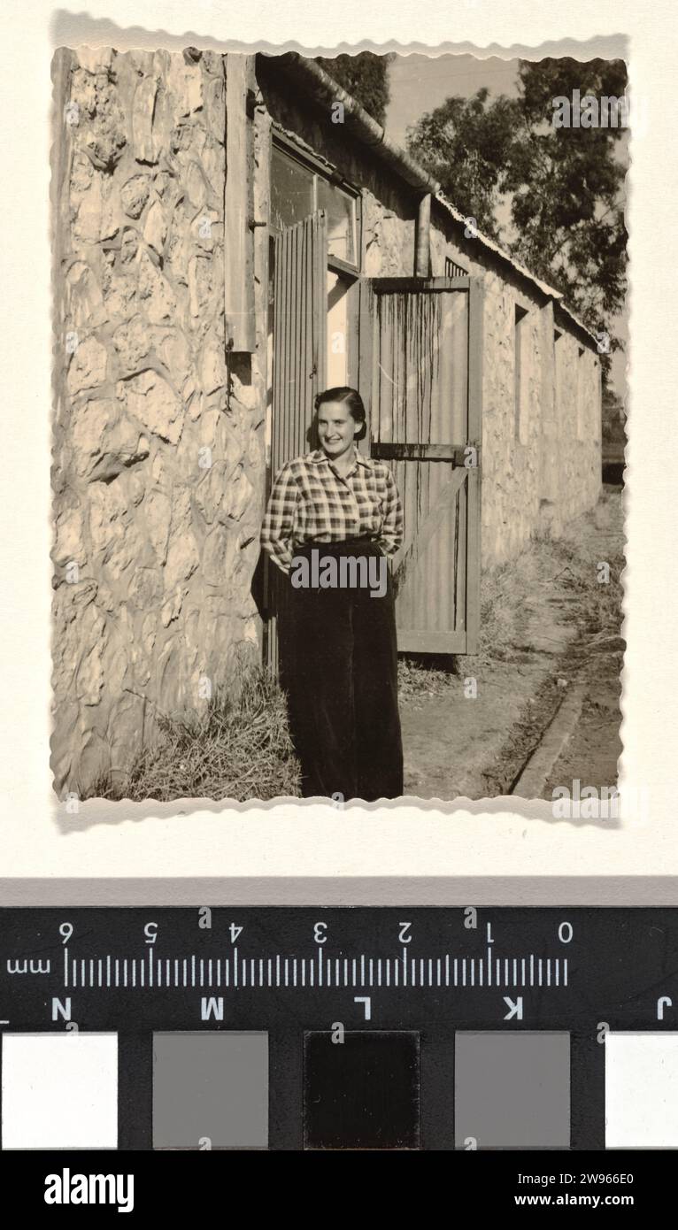 Isabel Wachenheimer in blocked shirt, standing in front of a building with doors and coarse stone wall, airport of LOD in November 1952, Anonymous, 1952 photograph Isabel Wachenheimer in blocked shirt, standing in front of a building with patio doors and coarse stone wall, LOD airport.  photographic support gelatin silver print Stock Photo