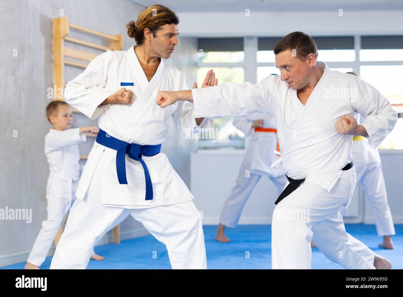 Man in kimono and colored belt practicing karate punch block whith
