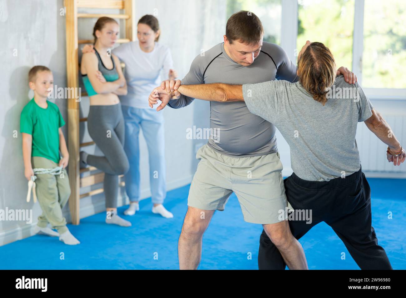 Man with trainer in self-defense training in gym practices trip up opponent during sparring Stock Photo