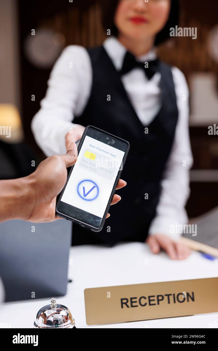 Guest paying with nfc on phone at pos terminal, hotel staff helping ...