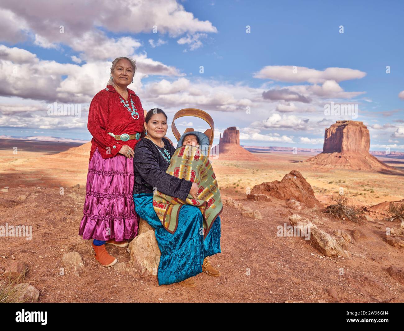 Monument Valley, Arizona, USA - Oct 07 2018: Two native American Navajo members, women with a baby in a papoose in the red-sand desert in the Navajo N Stock Photo