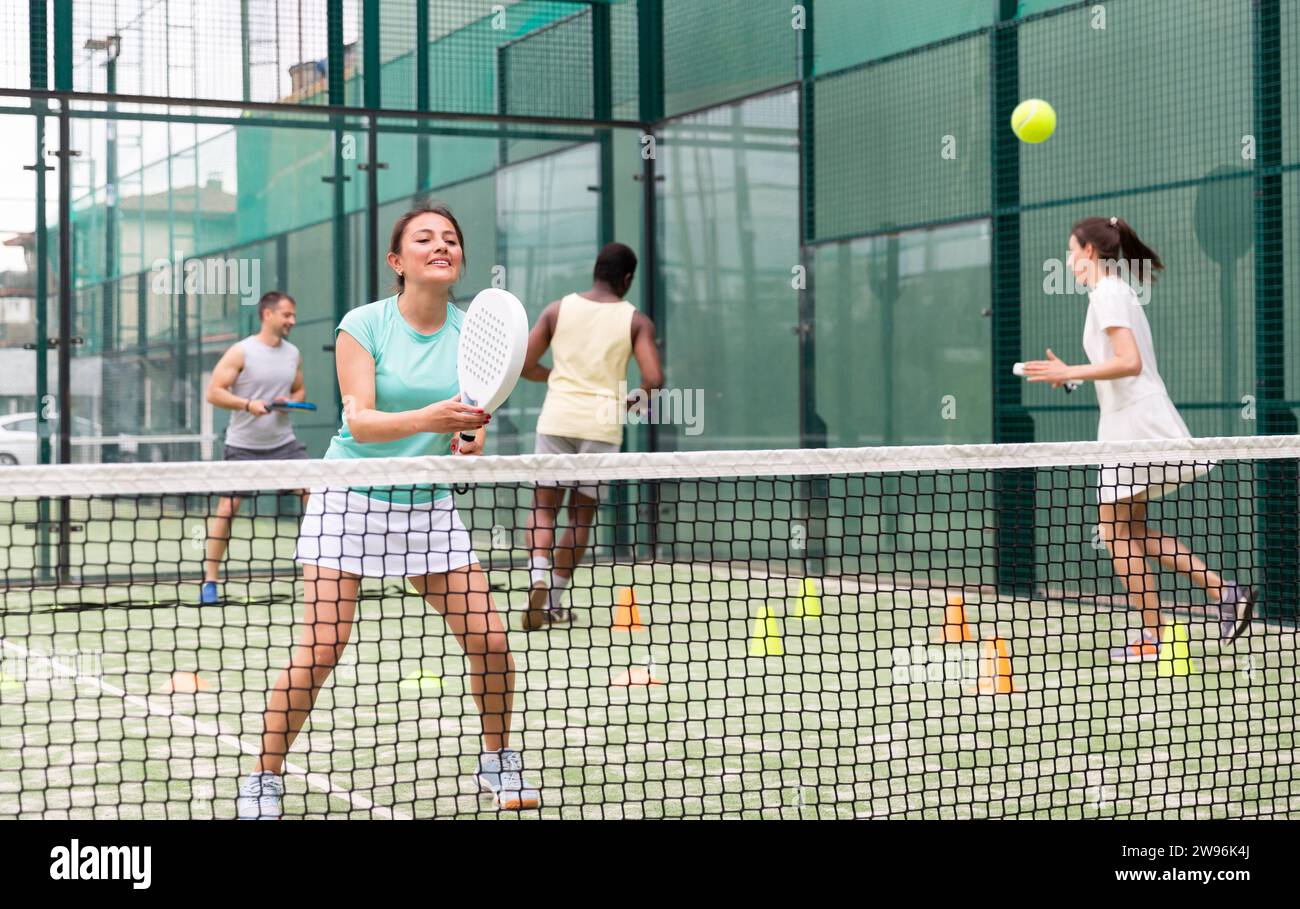 Portrait of cheerful woman paddle tennis player performing strokes