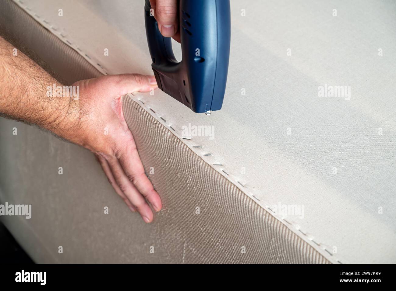 Worker stapling sofa lining with electric staple gun Stock Photo