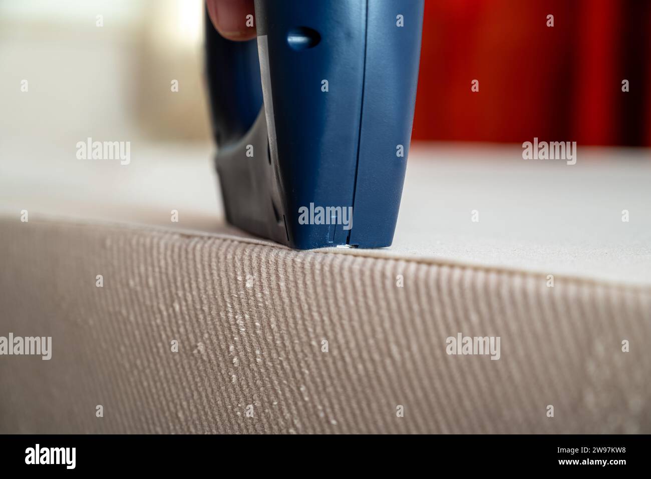 Worker stapling sofa lining with electric staple gun Stock Photo