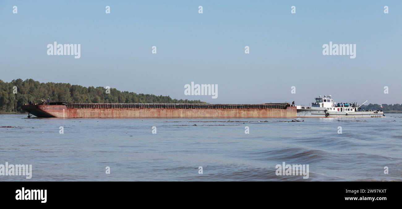 A pusher boat transports cargo barge along the Danube River Stock Photo