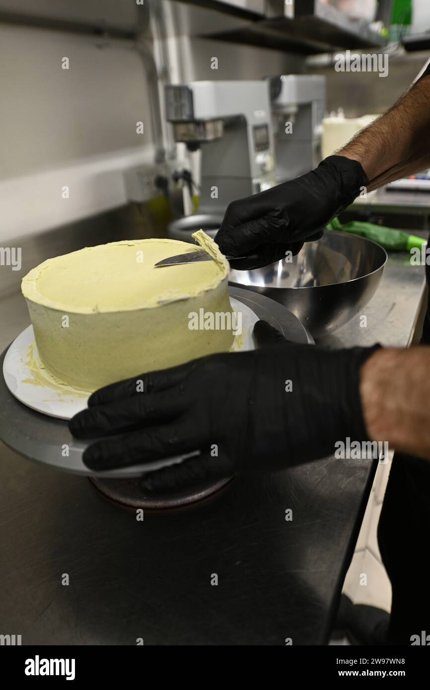 pastry chef wear gloves prepare pistachio frosted icing cake for